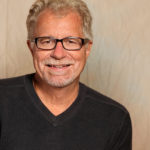 Fred Ode (headshot of Fred Ode in a black sweater with dark-rimmed rectangular glasses)